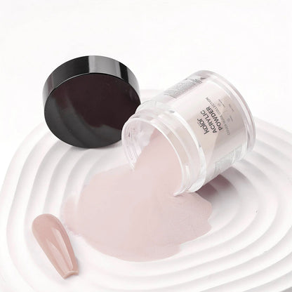 A clear jar of nail powder with its black lid beside it, tipped over so the pale pink powder spills onto a white surface. A matching pink nail tip sample lies nearby.