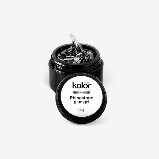 An open black jar of Kolor Rhinestone Glue Gel with a clear gel swirl visible at the top, shown with its white and black lid placed in front on a light gray background.