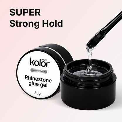 Kolor anti-gravity rhinestone glue gel in a black jar with its lid beside it, showing a clear gel being drawn up with a brush on a pale pink background with 'SUPER Strong Hold' text.
